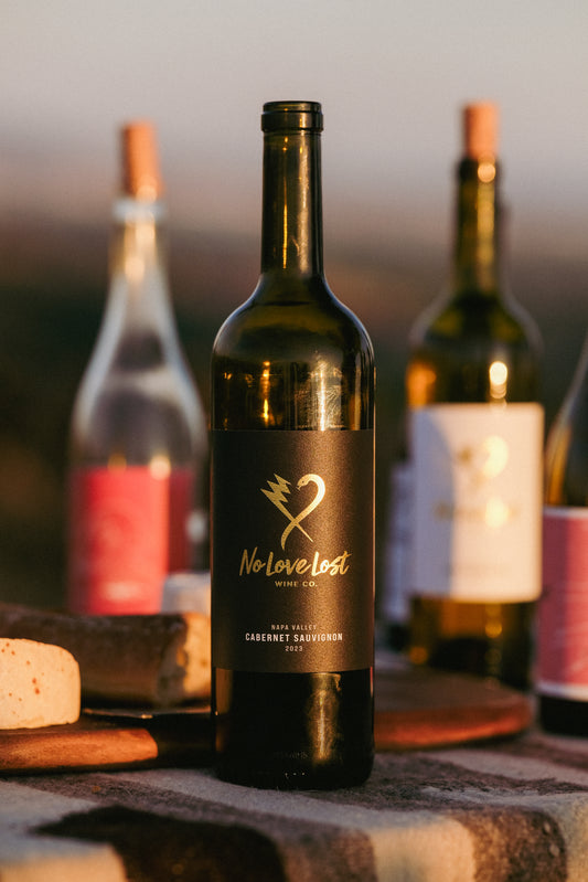 2023 No Love Lost Cabernet Sauvignon — 100% Cabernet from organically farmed vineyards in Coombsville, Silverado Bench, and Oak Knoll District, Napa Valley. Rich black fruit, blackberry, black currant, and blueberry flavors. Full-bodied with velvety texture, balanced acidity, integrated tannins, aged 22 months in new Bordelaise French oak. 14.2% ABV."